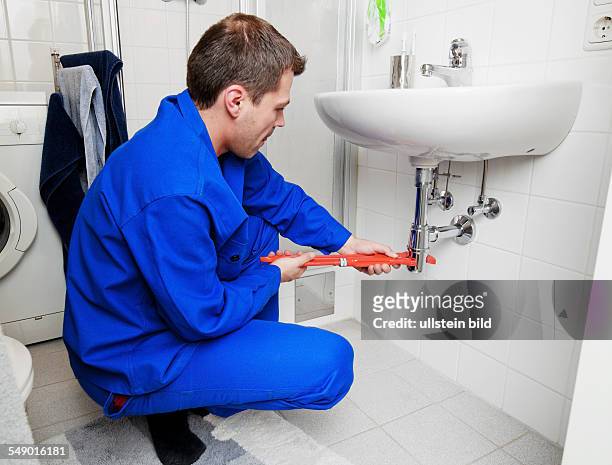 Ein Klemptner repariert ein kaputtes Waschbecken in Badezimmer