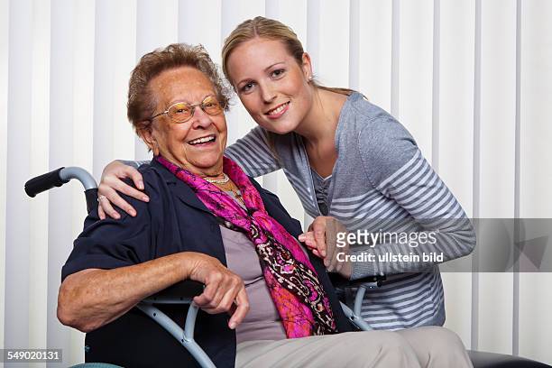 Ein Enkelin besucht seine Großmutter, die im Rollstuhl sitzt.