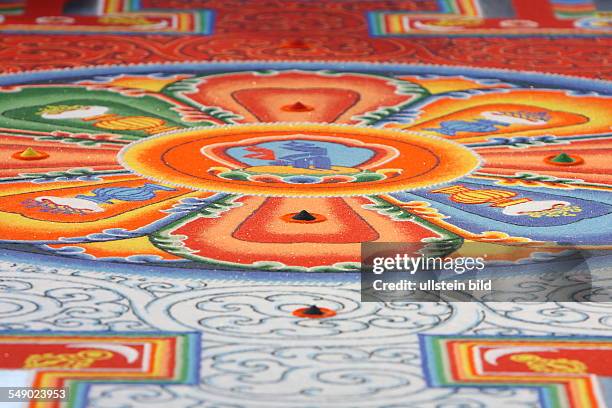 Monks from Bhutan strew a sand mandala.