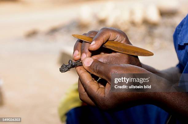 Cameroon, Foumban: Casting bronze figurines in the lost-wax process. Here: molding the wax figurine