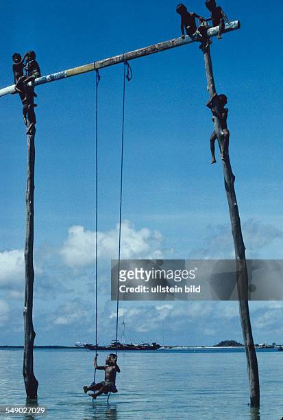 Philippines, Sulu sea: Badjao children climbing up a pole stuck in the water of the island Marunga.
