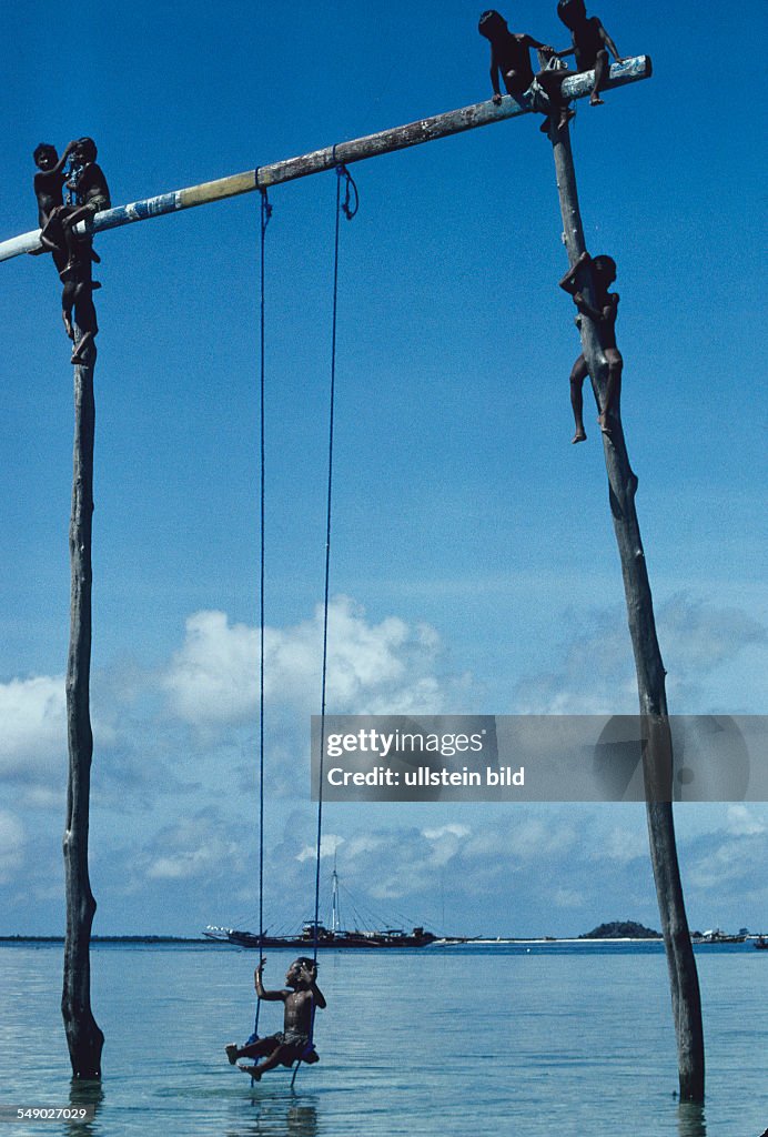PHL, Philippines, Sulu sea: Badjao children climbing up a pole stuck in the water of the island Marunga.