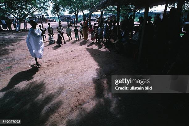 The witchdoctor s assistant begins to dance covering himself with white kaolin to symbolize spiritual death and purification