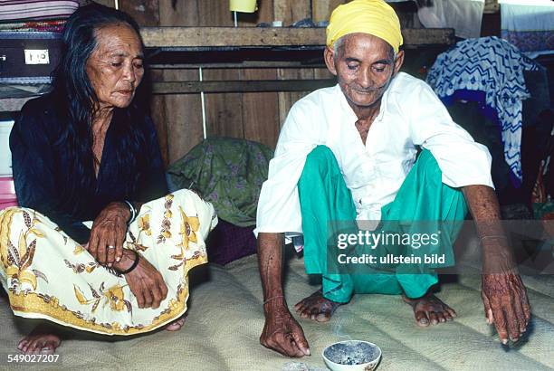 Philippines, Sulu sea: A Badjao shaman treating a woman who is possessed by a bad spirit. She inhales the incence he is burning.