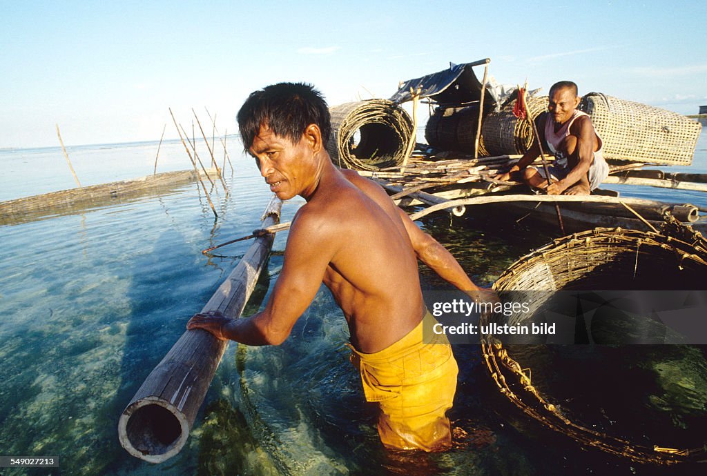 PHL, Philippines, Sulu sea: A Badjao fisherman puts out bamboo nets called Ampas near the island of Siasi.