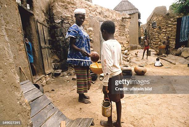 The followers of a Marabout begging for food in a Dogon village. -