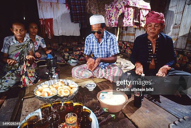 Philippinen, Sulu sea: A Badjao shaman and his son preparing a feast for their ancestors who reside in the textile tent in the background.