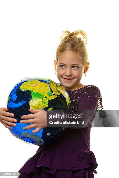Ein kleines Mädchen sieht sich einen Globus an.