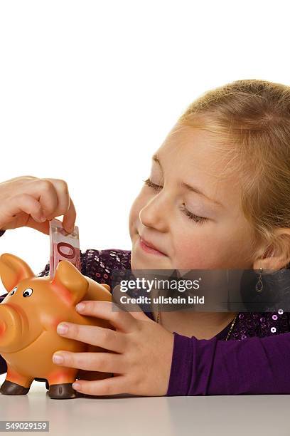 Ein kleines Kind steckt einen Geldschein in ein Sparschwein. Euroschein.
