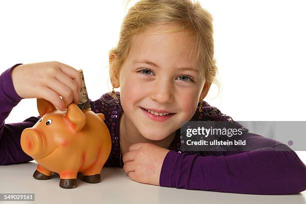 Ein kleines Kind steckt einen Geldschein in ein Sparschwein. Dollar.