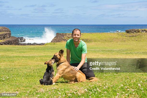 handsome man playing with dogs at easter island - easter_island stock pictures, royalty-free photos & images