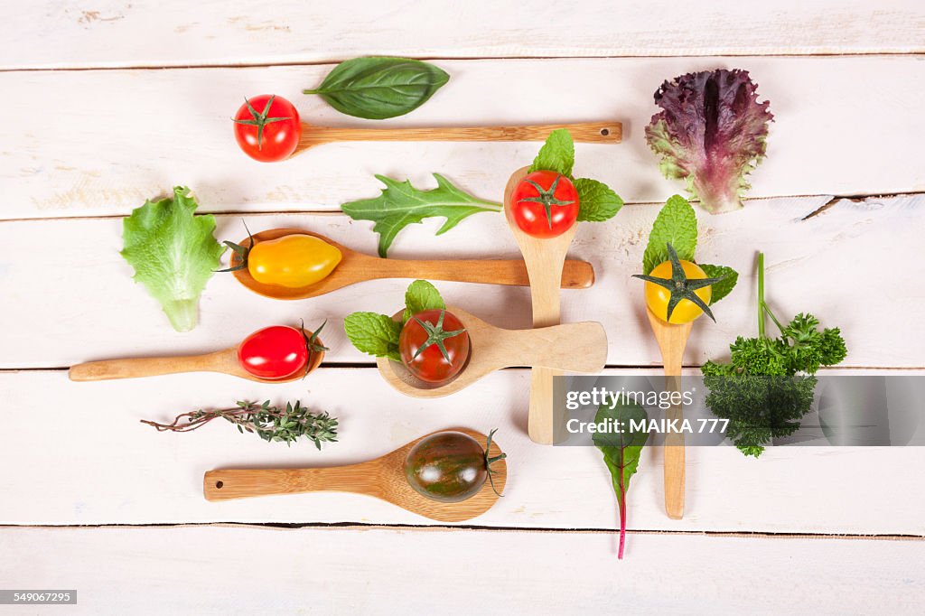 Cherry tomatoes, lettuce and herbs on wooden spoon