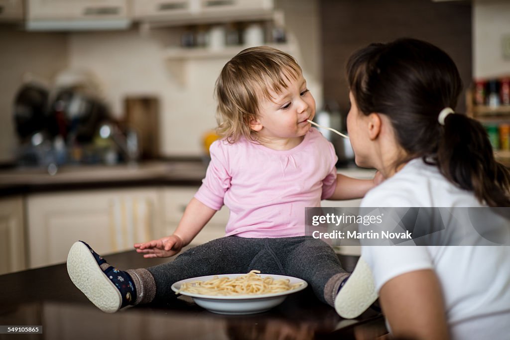 Mother and child eating spaghetti together