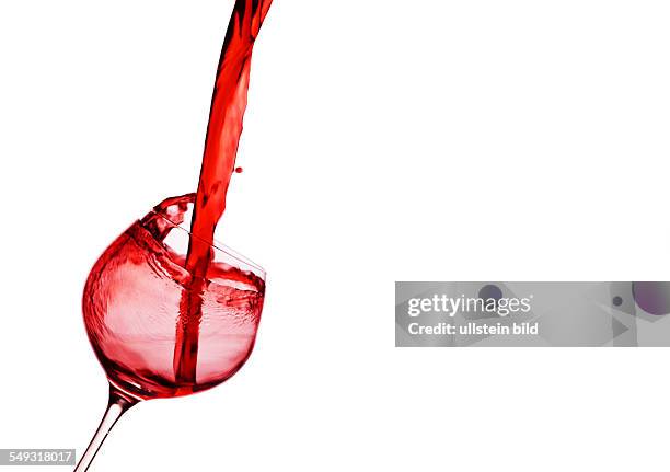 In ein Glas wird roter Wein eingegossen. Rotwein im Rotweinglas