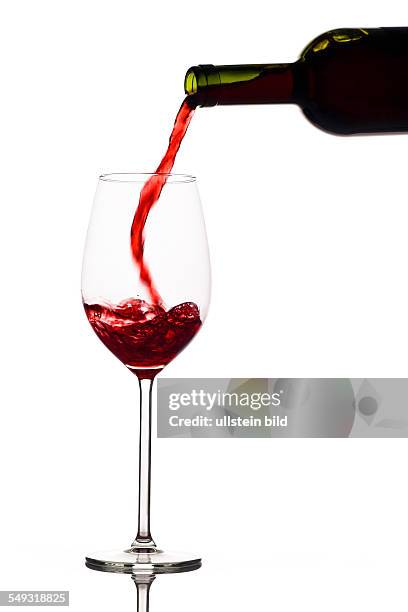 In ein Glas wird roter Wein eingegossen. Rotwein im Rotweinglas