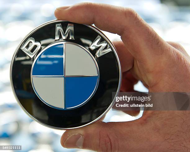 Ein Mitarbeiter haelt ein BMW Emblem in der Hand bei der Produktion des neuen BMW 3er im Werk Regensburg, 12 Maerz 2012.