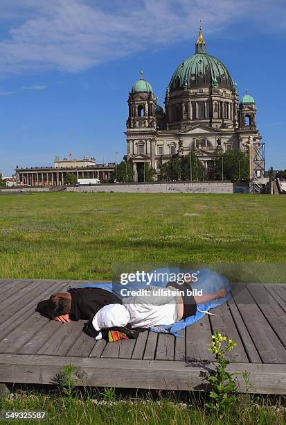 Berlin, Paar schläft auf Holzsteg auf der Schlossplatzwiese, im Hintergrund der Berliner Dom