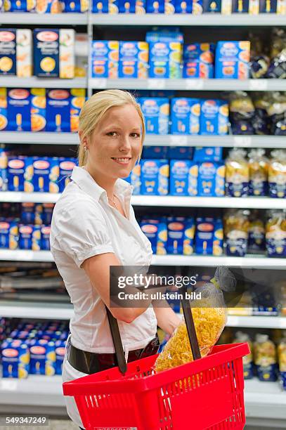 Eine junge Frau beim Einkauf mit einem Einkaufswagen in einem Supermarkt.