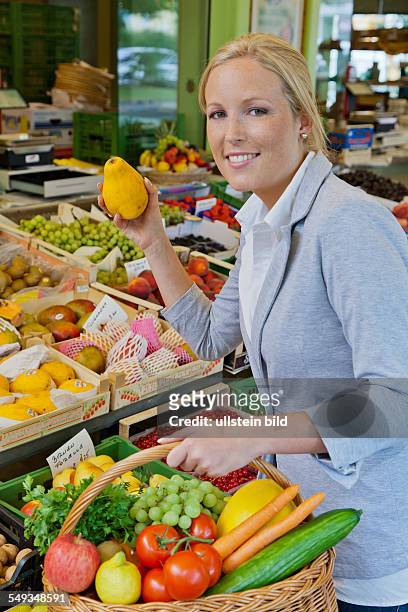 Eine junge Frau kauft Obst und Gemüse auf einem Wochenmarkt. Frische und gesunde Ernährung.