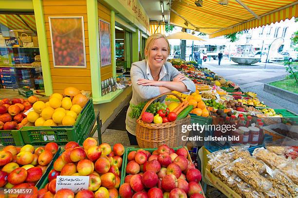 Eine junge Frau kauft Obst und Gemüse auf einem Wochenmarkt. Frische und gesunde Ernährung.