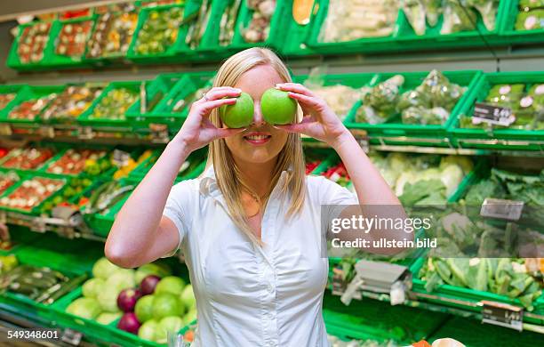 Frau beim Einkauf von Obst und Gemüse im Frischeregal eines Supermarktes