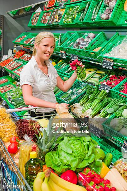 Frau beim Einkauf von Obst und Gemüse im Frischeregal eines Supermarktes
