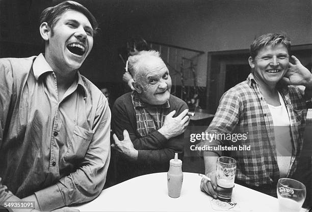 Germany, Hessen, men in a village inn having fun by making jokes.