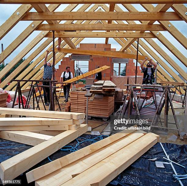Carpenters construct a roof truss for a house.