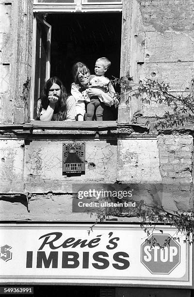 Familie mit Kind am Fenster ueber einer Imbissbude "René's Imbiss Stop", , verfallene Fassade, Gasaussenwandheizung