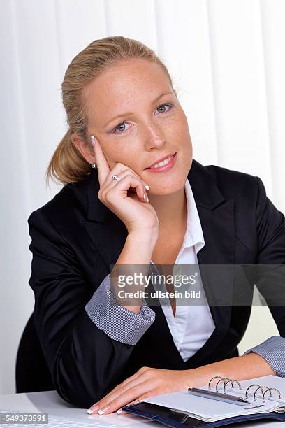Eine junge, erfolgreiche Geschäftsfrau sitzt an ihrem Schreibtisch im Büro
