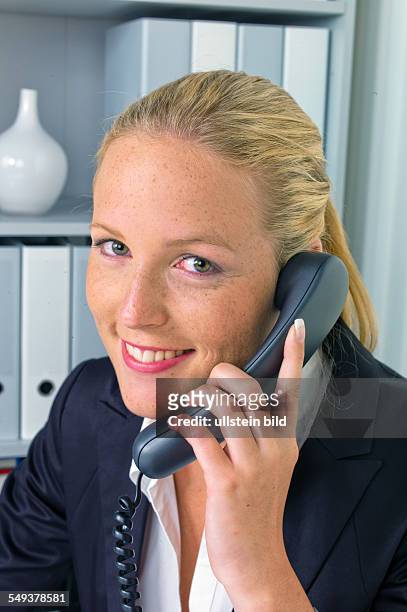 Eine freundliche Frau telefoniert an ihrem Schreibtisch im Büro