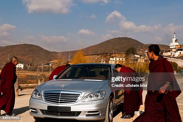 Moenche betrachten einen Mercedes Benz vor dem Kloster Gandem Sumtseling