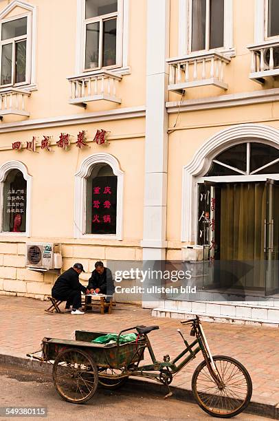 Qingdao, Shanxi Lu, Maenner beim Spielen vor einem alten Kolonialgebaeude