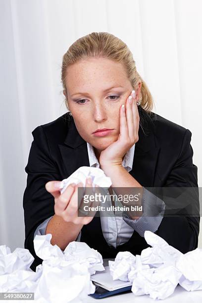 Eine Frau im Büro mit zusammengeknülltem Papier. Ärger, Stress und Frust am Arbeitsplatz