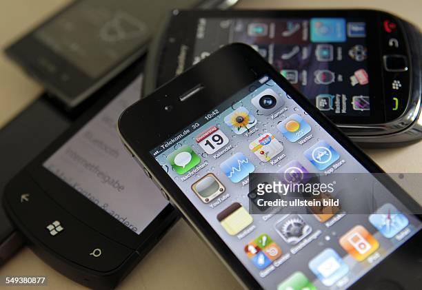Smartphones / Handys verschiedener Herstelelr liegen auf einem Tisch , oben ein Apple iPhone 4