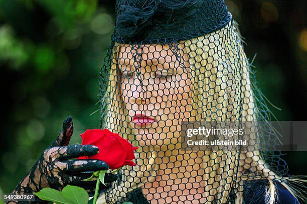 Eine junge, trauernde Witwe mit Schleier und Rose. Todesfall und Erbschaft.