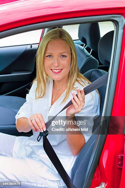 Eine junge Frau gurtet sich vor der Fahrt in einem Auto mit dem Sicherheitsgurt an.