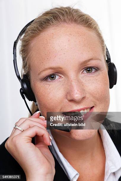 Eine freundliche junge Frau mit Headset im Kundendienst telefoniert mit einem Kunden