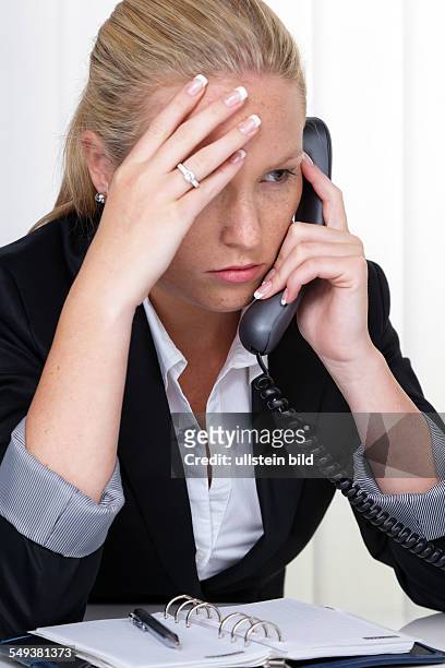 Eine frustrierte Frau telefoniert im Büro. Stress und Überforderung am Arbeitsplatz.