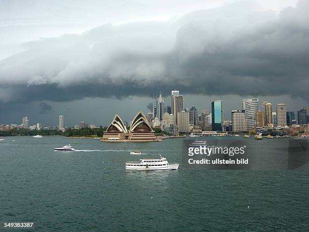 Bedrohliche Gewitterwolken ueber der Hafenstadt Sydney. Bildmitte: das Opernhaus.