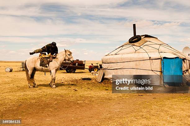 Die Grassteppe Hulun Buir mit einem Mongolen auf einem Pferd und einer Jurte im Hintergrund