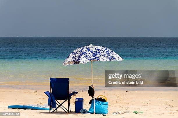 Beach umbrella and deck chair on sandy beach, Coral Bay, Western Australia