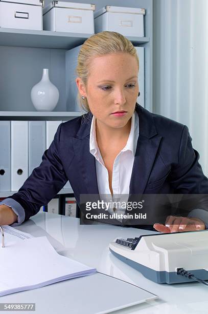 Eine Buchhalterin bei der Arbeit im Büro mi Tischrechner