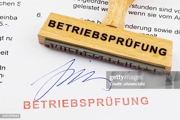 Ein Stempel aus Holz liegt auf einem Dokument. Deutsche Aufschrift: Betriebsprüfung