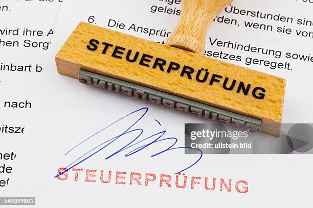 Ein Stempel aus Holz liegt auf einem Dokument. Deutsche Aufschrift; Steuerprüfung