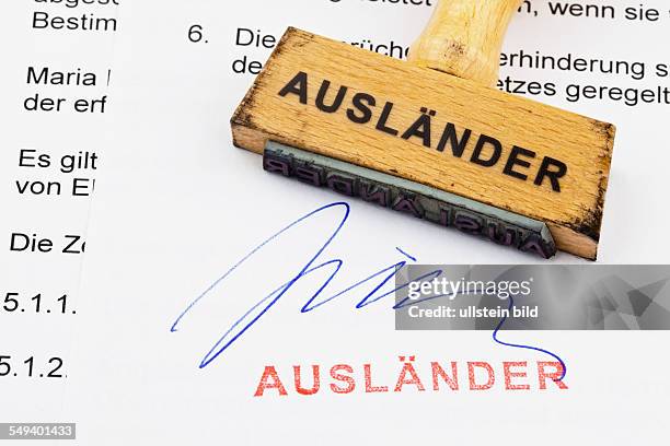 Ein Stempel aus Holz liegt auf einem Dokument. Deutsche Aufschrift: Ausländer