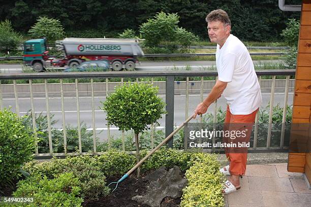 Germany, Reportage "Living at the highway 40". Essen. Man working in his garden next to the expressway