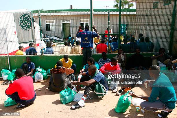 Spain, Melilla: Centro de Estancia Temporal de Inmigrantes CETI in the spanish exclave. Migrants sitting on the floor with their clothes in plastic...