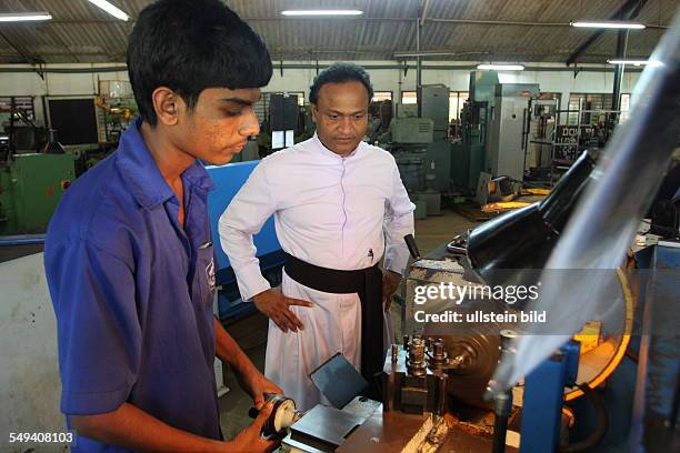 Sri Lanka, Negombo: Father Shiran, leader of the Don Bosco technical center and a trainee working on a maschine