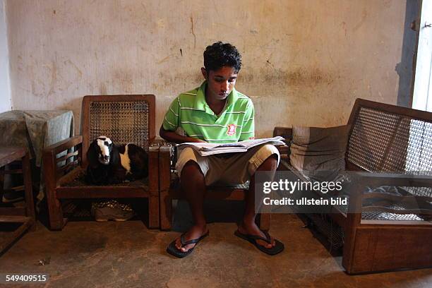 Sri Lanka, Kandy: Pupil of the Don Bosco center for vocational training for former street kids or children of poor families. He reads a book, next to...